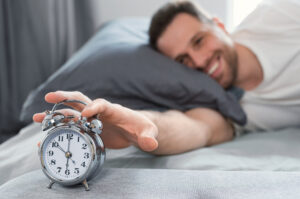 man waking up shutting off alarm clock